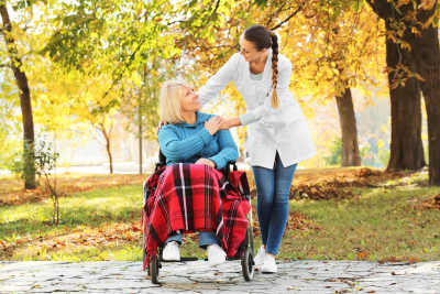 senior in wheelchair accompanied by nurse