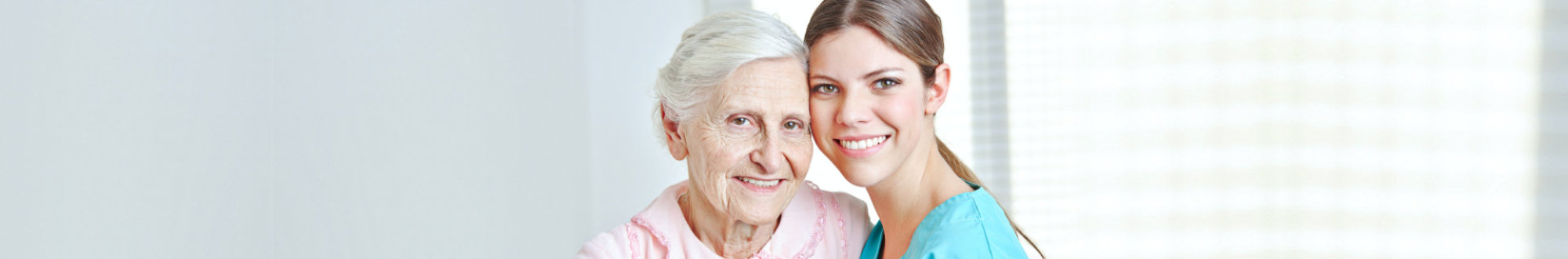 Smiling caregiver embracing happy senior women in nursing home