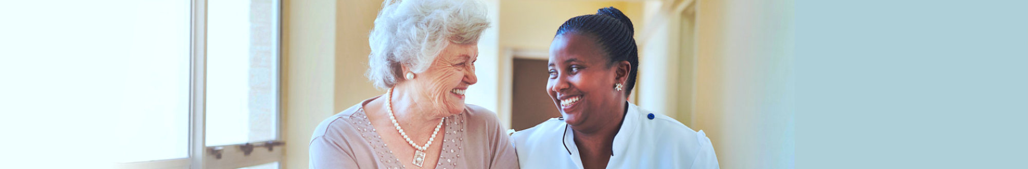 smiling home caregiver and senior women walking together